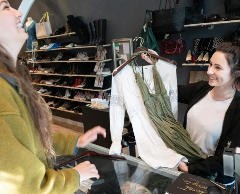 Woman buying white shirt and green dress from a Closet Trading Company Clothing Franchise